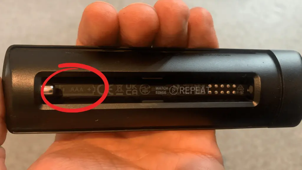 Firestick remote battery compartment with red circle highlighting the correct battery orientation.