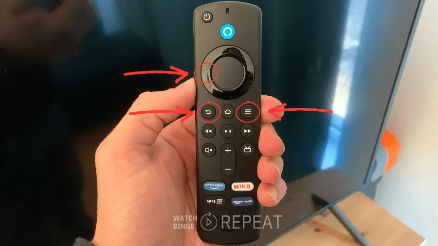 A hand holding a black Firestick remote with red arrows pointing to the back button, menu button and left button on ring key