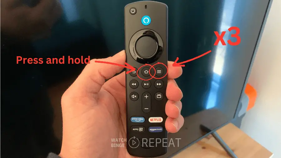 A hand holding aFirestick streaming remote with red text and arrows indicating to press and hold the 'Home' button and click three times on the 'Menu' button