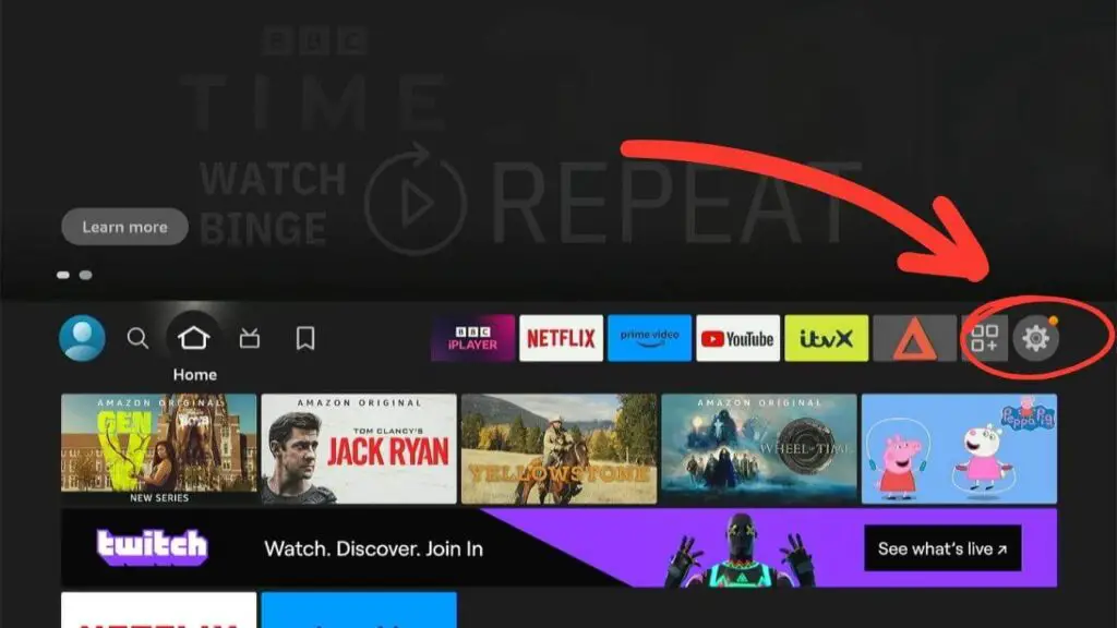 A screenshot firestick home screen, displaying various streaming service apps like BBC iPlayer, Netflix, and Prime Video. An arrow points to the settings icon on the top right.