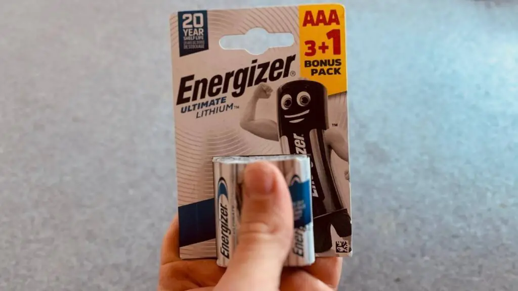 A hand presents a 3+1 bonus pack of Energizer Ultimate Lithium AAA batteries with a cartoon mascot