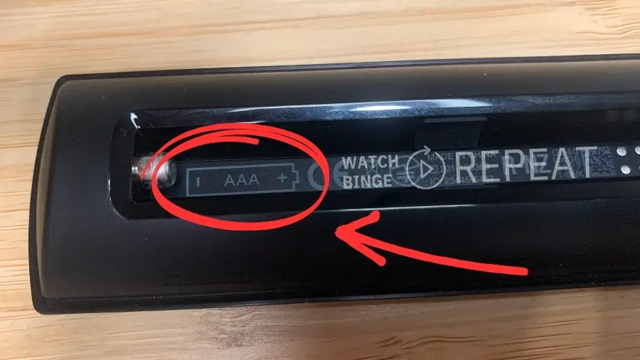 Arrow pointing to a place on a Firestick remote where you can find and information which type of battery you should put in (AAA) and which side the should be inserted