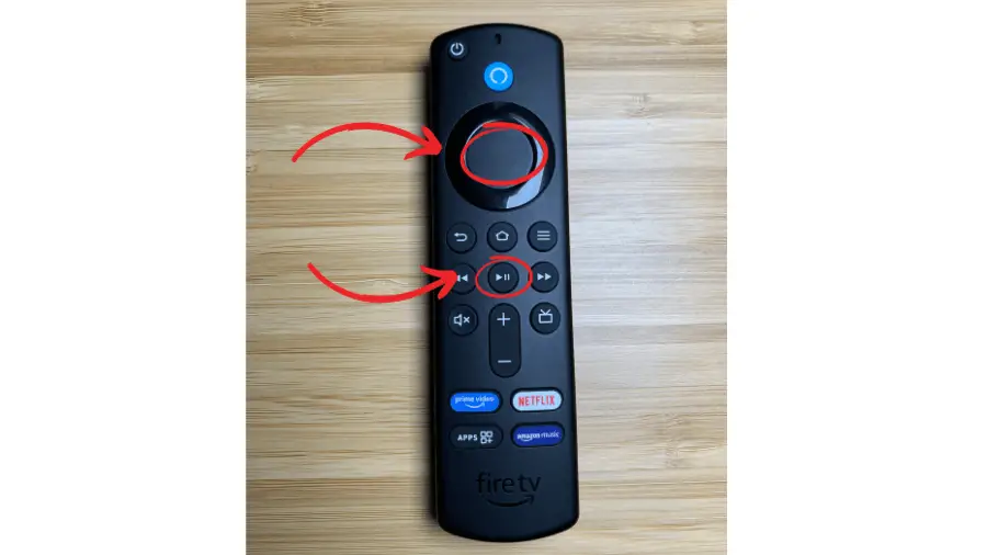 An Amazon Fire TV remote control with red arrows pointing to two buttons. The arrows indicate to press the circular navigation button in the middle and the play/pause button below it simultaneously.