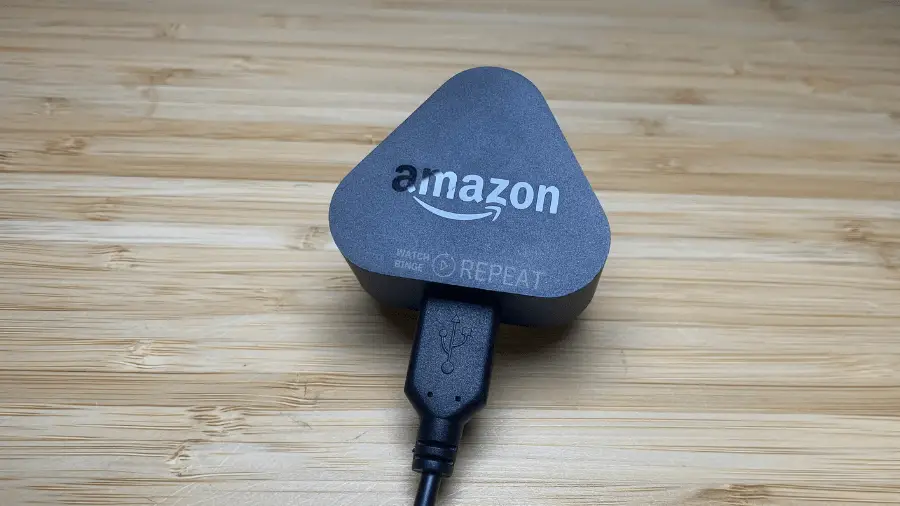 An Amazon Power Adaptrt for Fire TV Stick connected to a USB cable, placed on a wooden surface